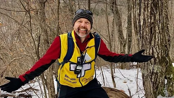 Photo of a volunteer in winter, with their volunteer vest.