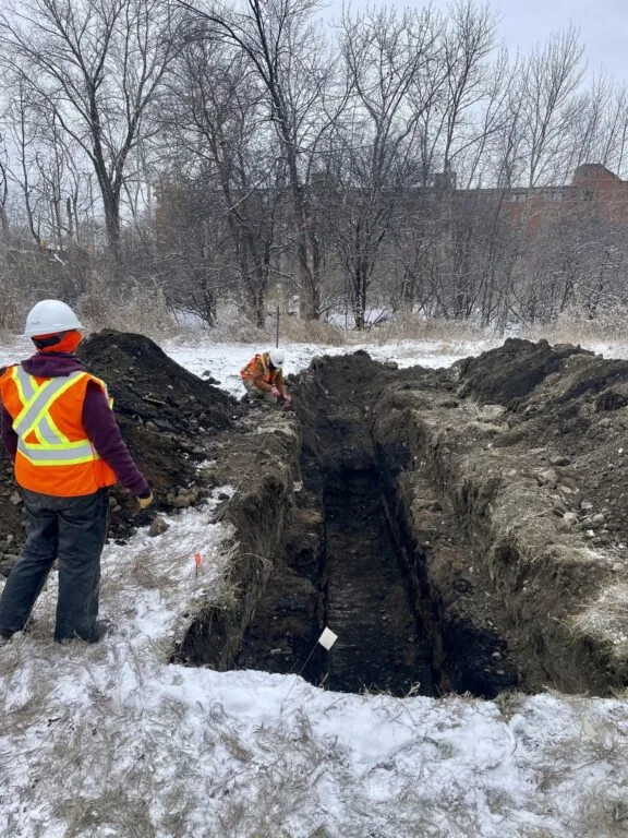 Worker beside a mechanically dug pit.