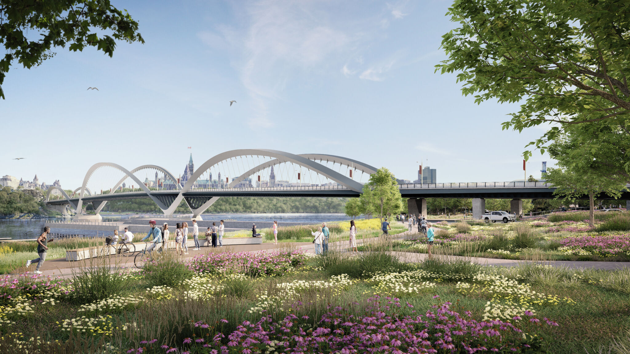 A view from Jacques Cartier Park in Gatineau, Quebec, showing the Alexandra Bridge with three undulating arches spanning the Ottawa River. The foreground features park pathways, colourful flowers and lush greenery, while the background includes the Ottawa skyline under a clear sky.