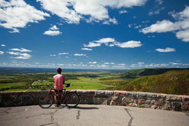 A cyclist admiring the view at the edge of the Champlain Lookout.