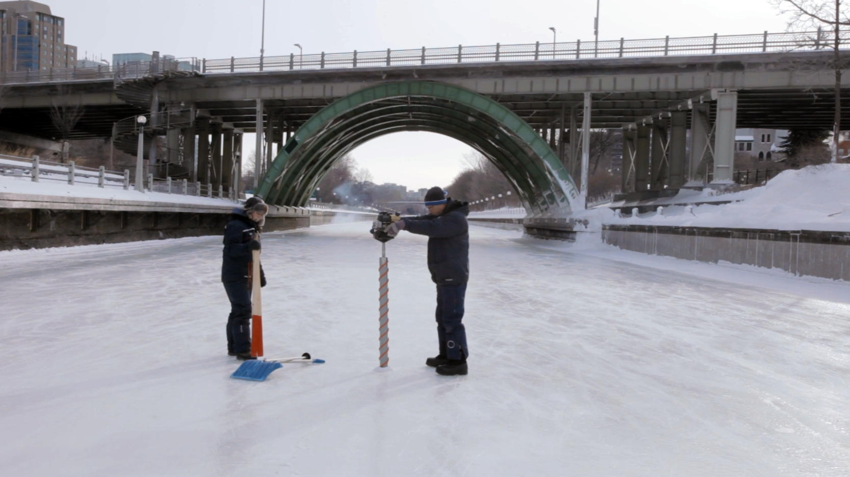 Staff collecting an ice sample (ice carrot) from the Rideau Canal Skateway.